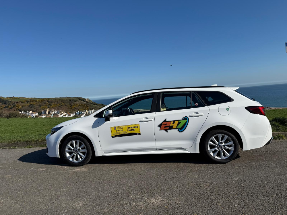 White 247 Taxis Toyota Corolla saloon estate on Hastings seafront